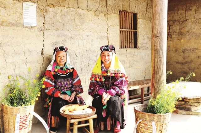 Lô Lô ethnic women sitting and shelling corn in front of their house. — Photo baodantoc.vn