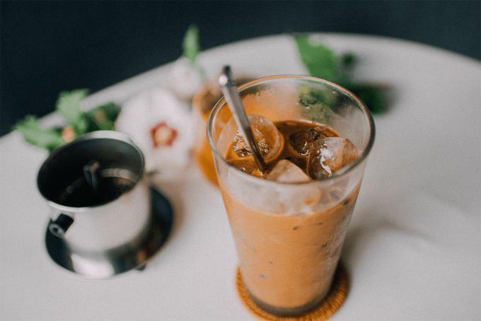 A stirred iced coffee showcases its caramel-brown hue, a blend of coffee and condensed milk. Photo by Mina